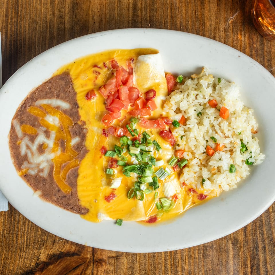 Good Times Grill's enchilada with refried beans, rice, cheese sauce, diced tomatoes, and green onions.