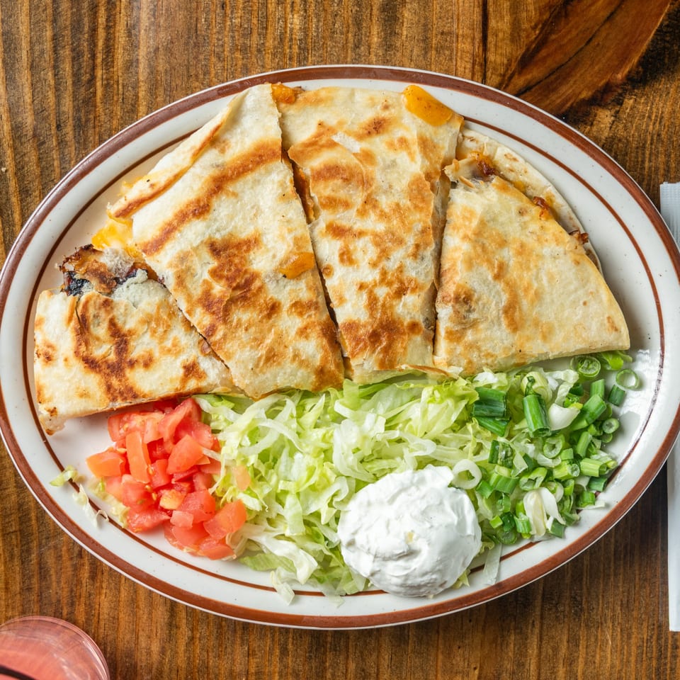 Good Times Grill's quesadilla with shredded lettuce, diced tomatoes, sour cream, and green onions.