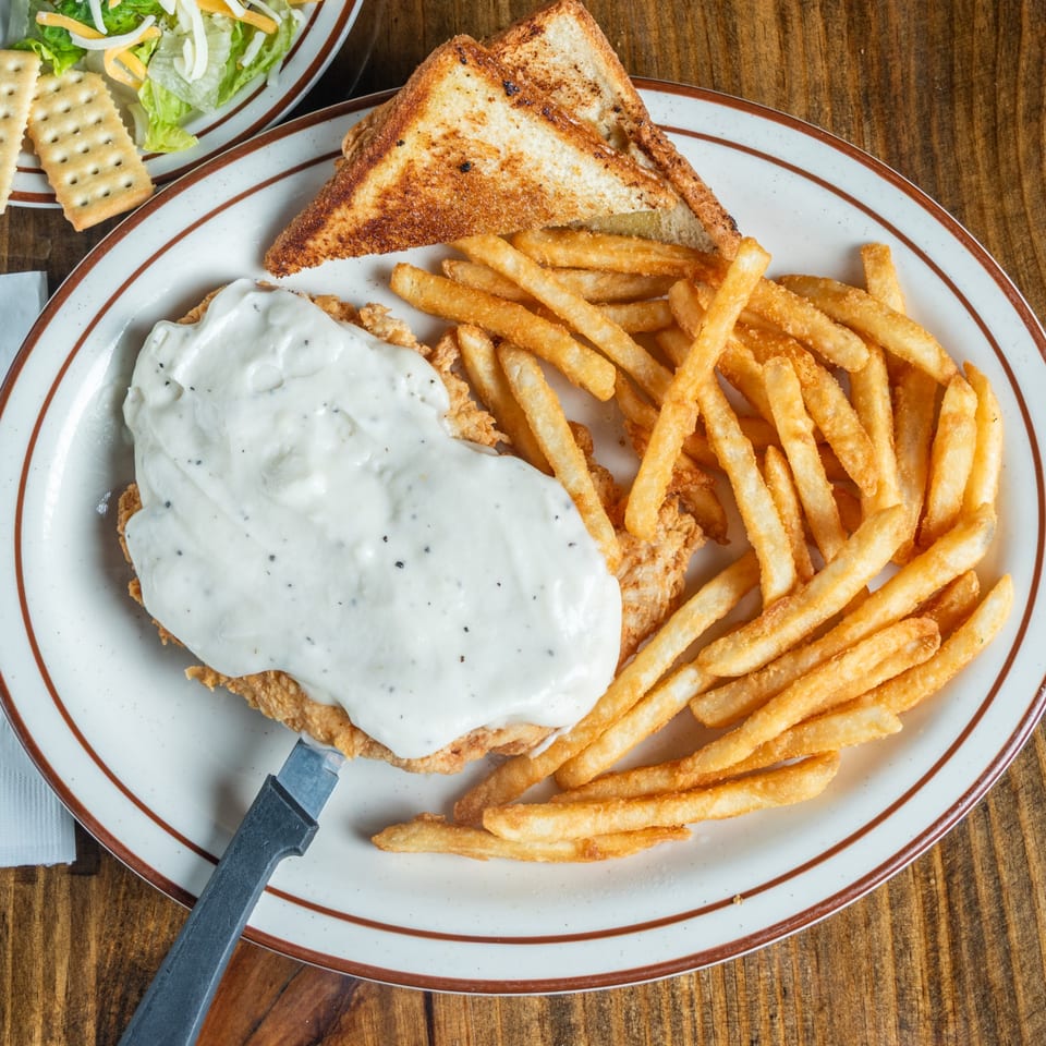 Good Times Grill's chicken fried steak with gravy, fries, and toast, with a side salad.