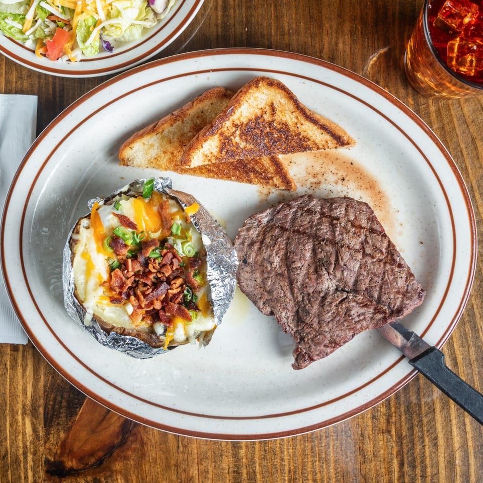 Good Times Grill steak dinner with a loaded baked potato, Texas toast, and a side salad.