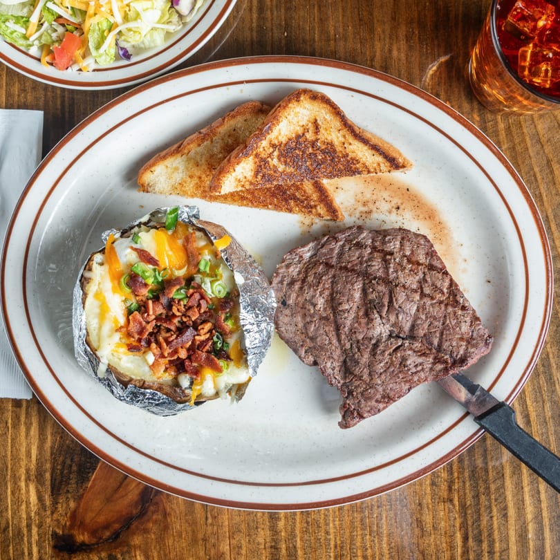 Good Times Grill steak dinner with a loaded baked potato, Texas toast, and a side salad.